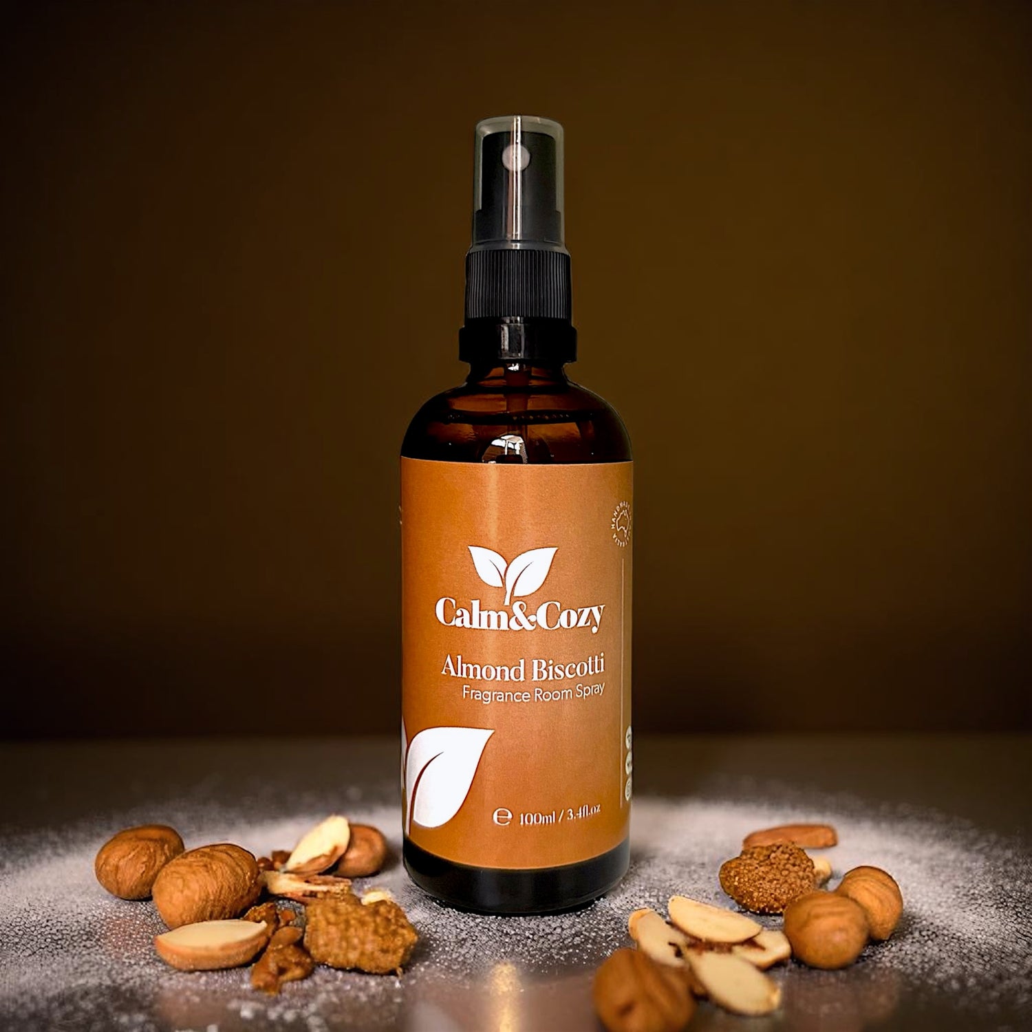 Bottle of Calm & Cozy Almond Biscotti fragrance room spray with almonds on a dark background