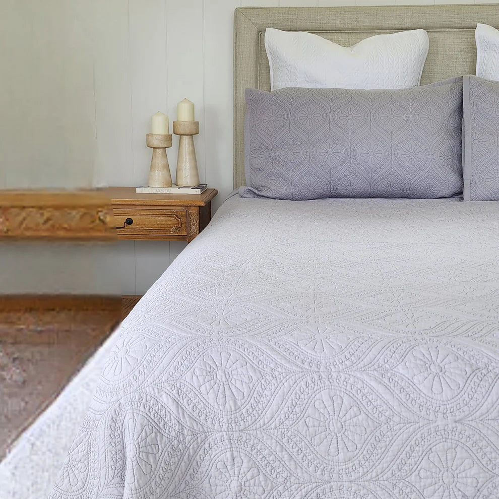 Bed with gray quilt and pillows in a bedroom setting