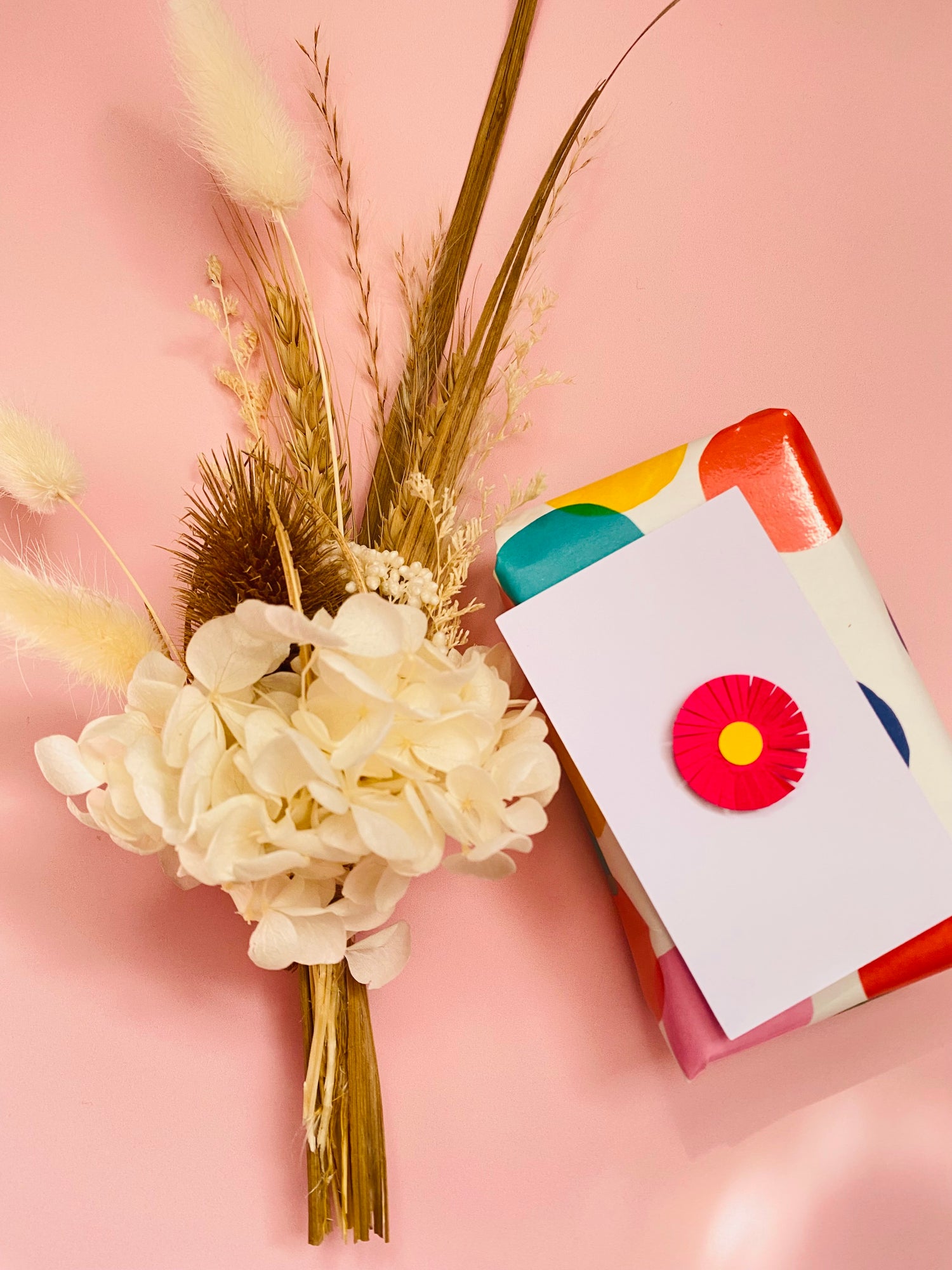 Bouquet of flowers with a colorful card on a pink background