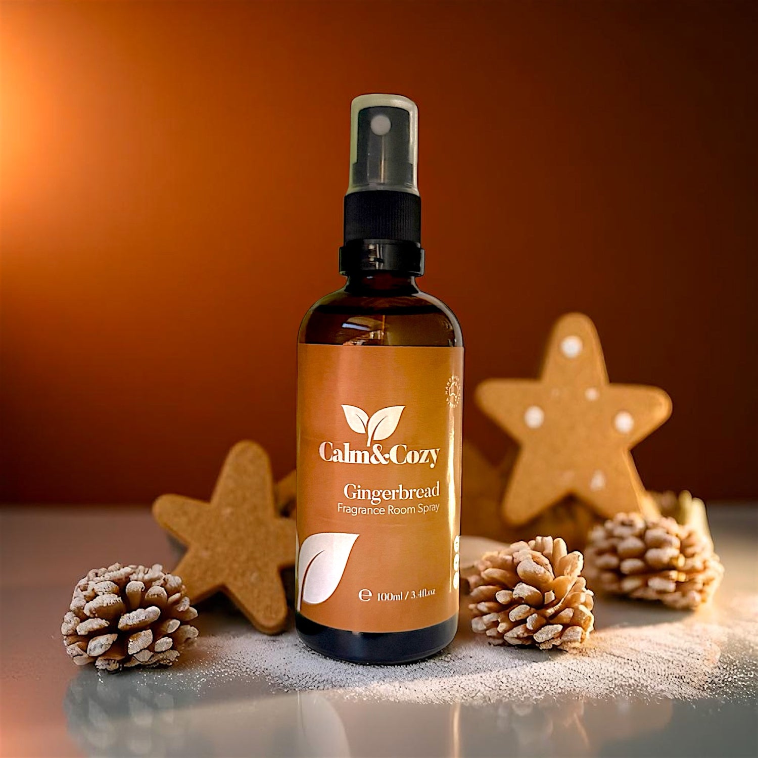 Bottle of Calm & Cozy Gingerbread Distance Room Spray with decorative stars and pinecones on a warm background