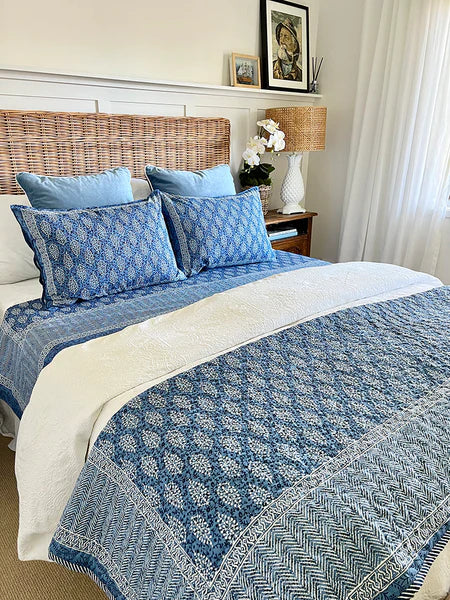 Bed with blue and white patterned bedding in a bedroom setting.