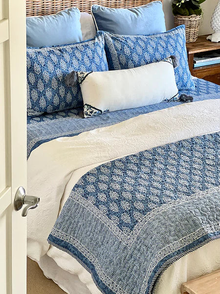 Bed with blue and white patterned bedding and pillows.