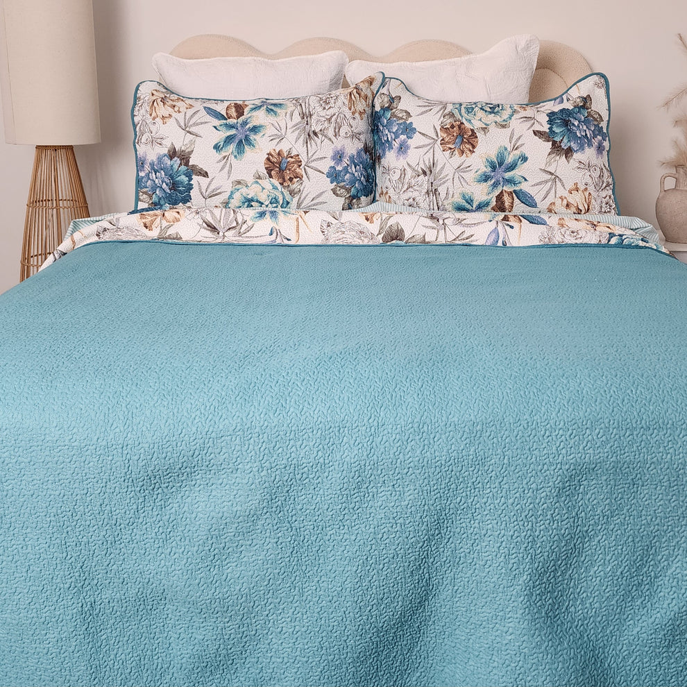 Floral-patterned pillows on a bed with a blue comforter