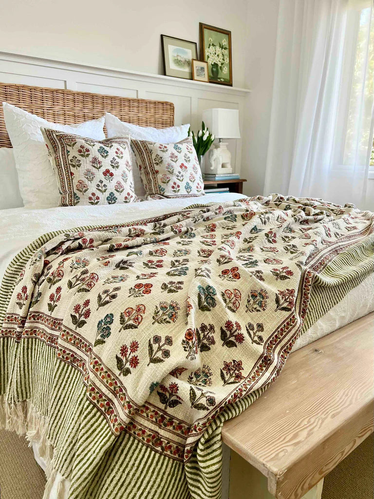 Bedroom with floral-patterned blanket on a bed, wooden bench, and framed pictures.