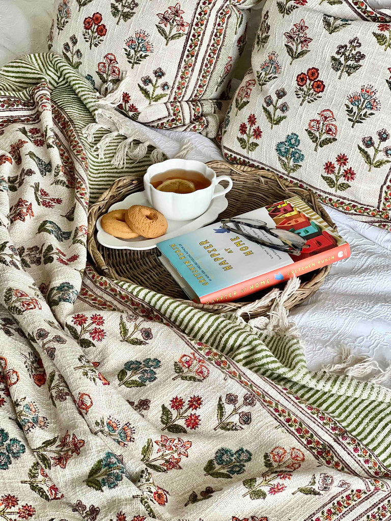Tray with tea, cookies, and books on a floral-patterned blanket