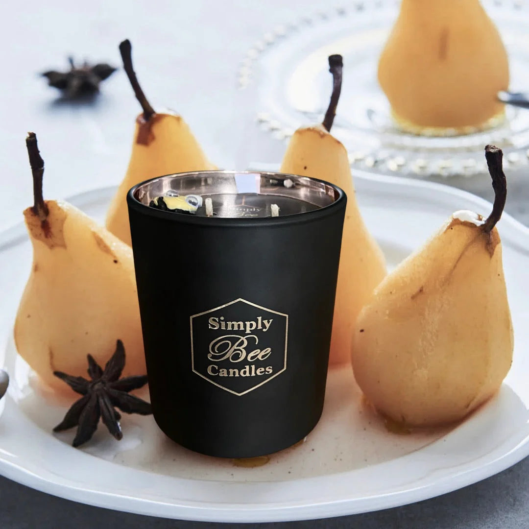 Black candle with 'Simply Bee Candles' logo on a white plate with pears and star anise.