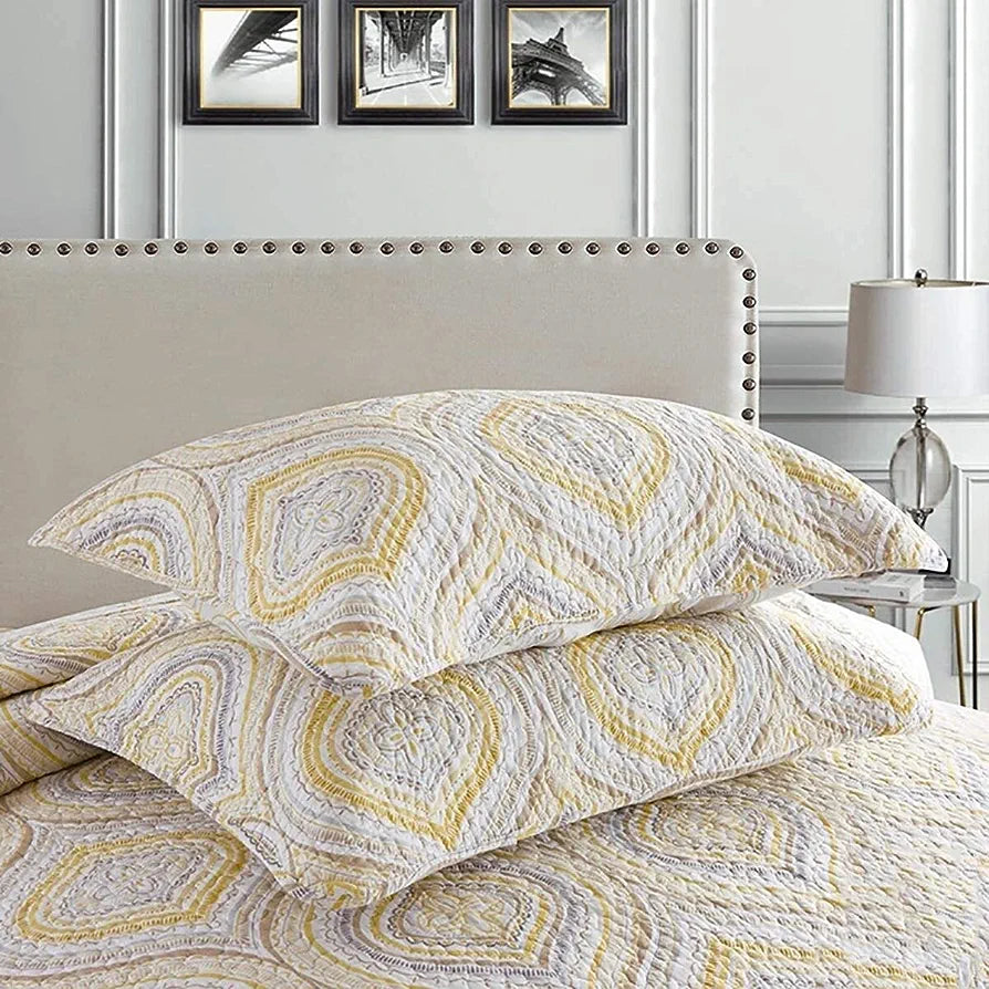 Patterned bedding set on a bed with a neutral headboard and lamp in the background.