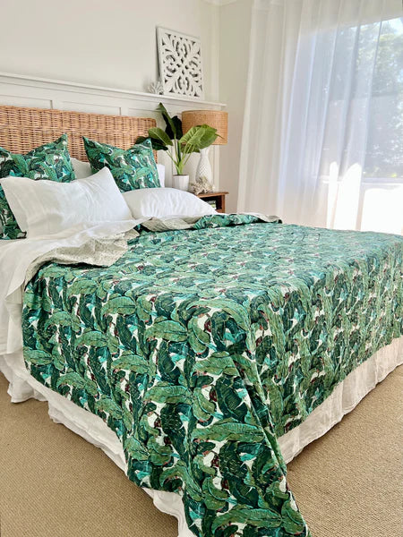 Bed with green leaf-patterned comforter in a bright bedroom