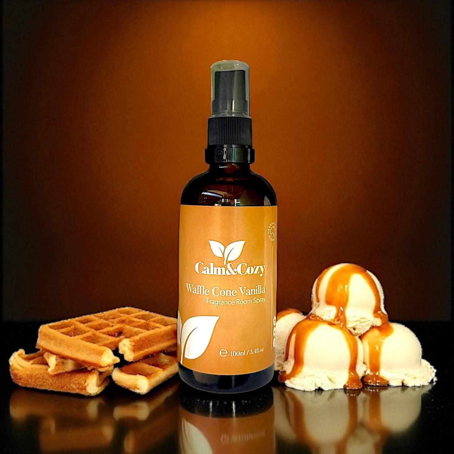 Bottle of Calm & Cozy Waffle Cone Vanilla spray with waffles and ice cream on a reflective surface.