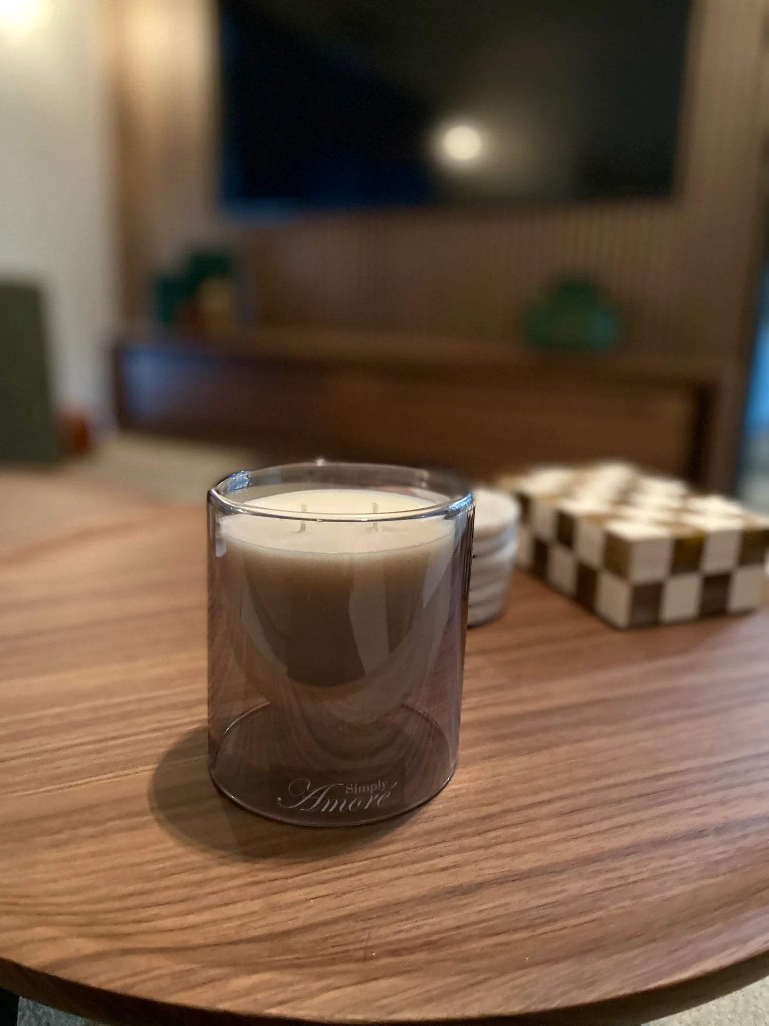 Candle in a glass holder on a wooden table with a blurred background