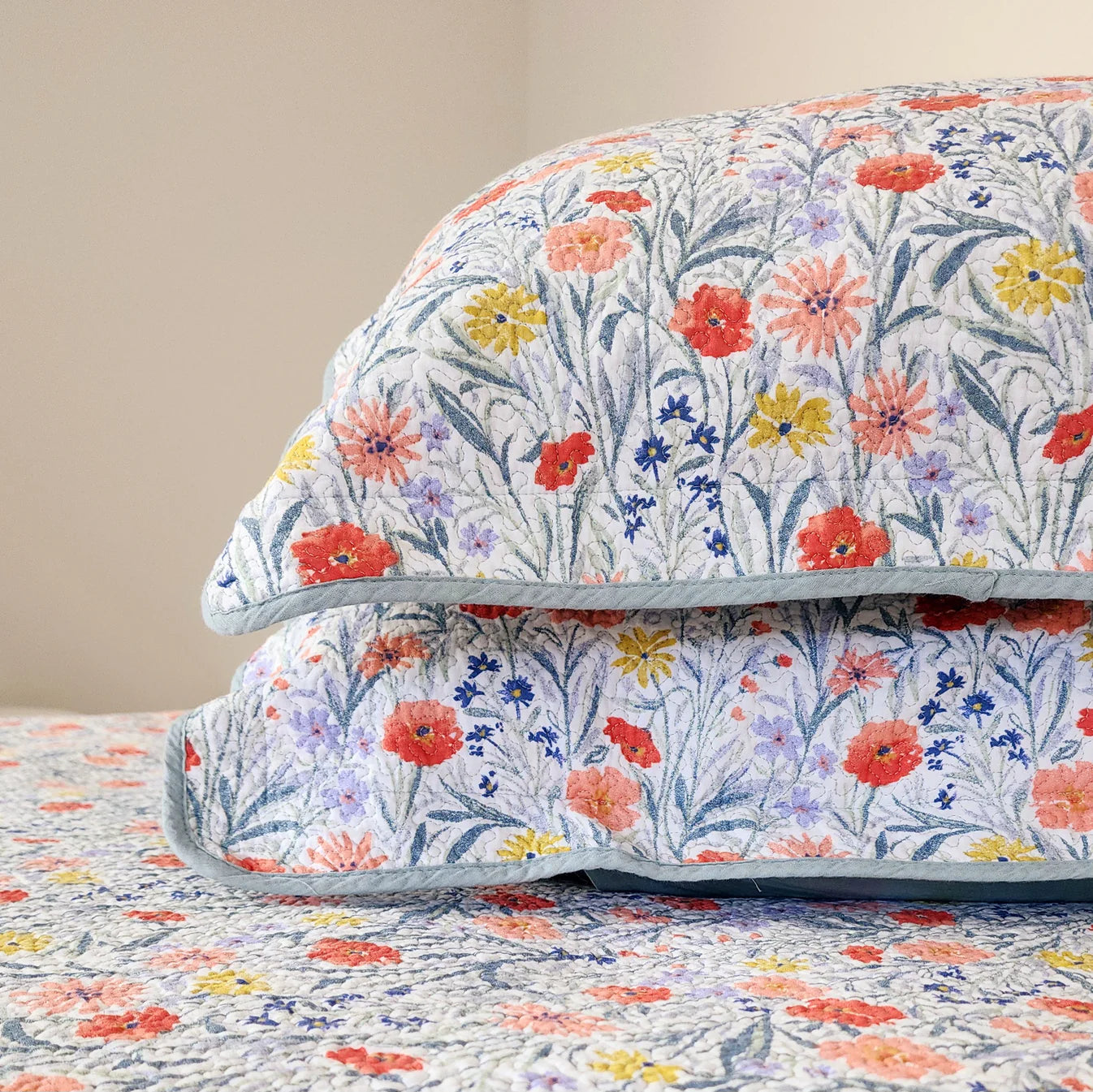 Floral-patterned comforter on a bed with a beige wall background