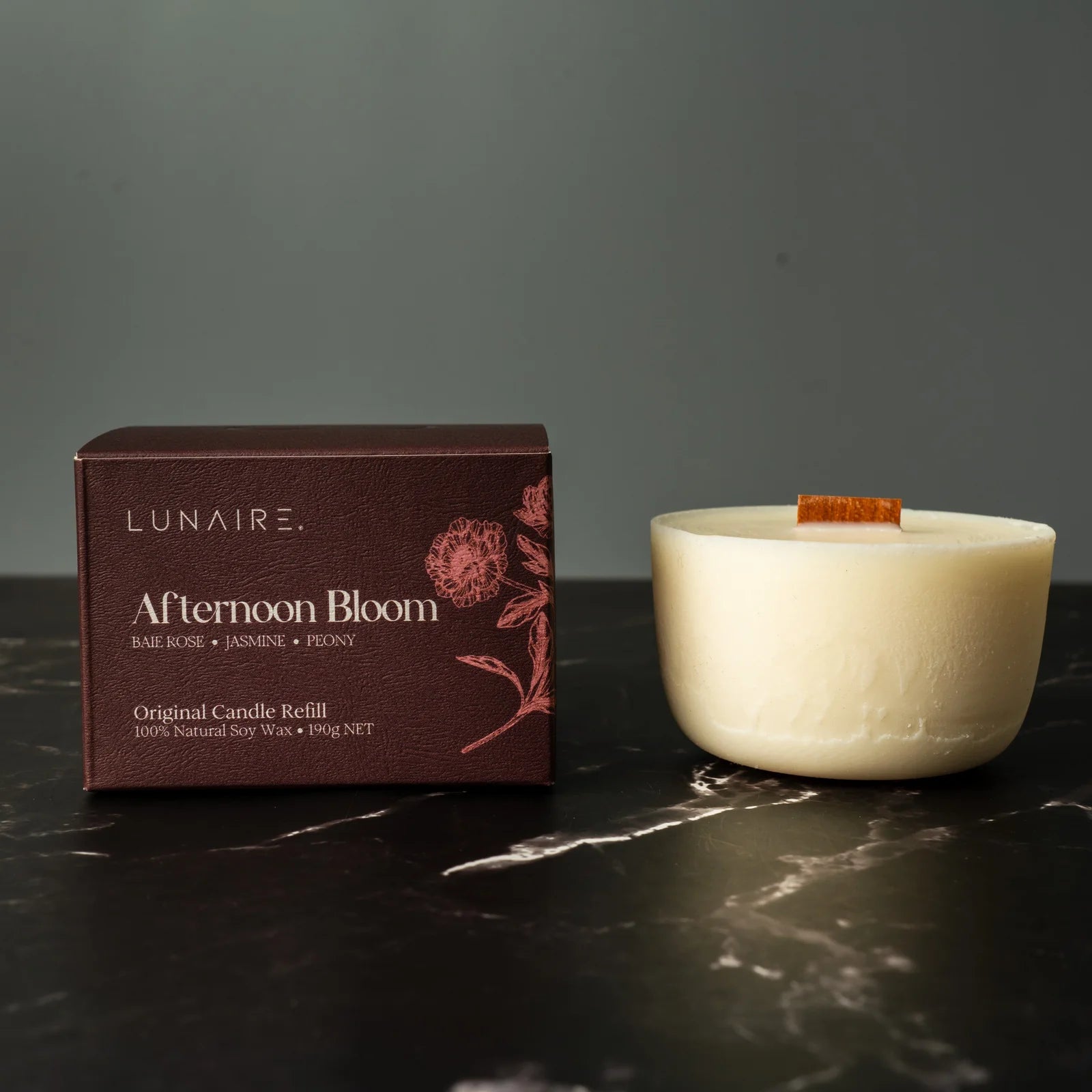 Lunaire Afternoon Bloom candle and packaging on a dark surface