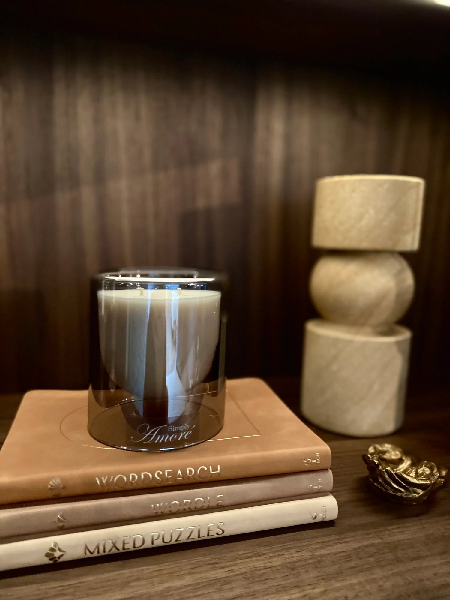 Candle in a glass holder on top of books with decorative items in the background