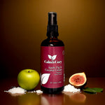 Bottle of Calm & Cozy room spray with an apple, fig, and coconut cream theme on a brown background.