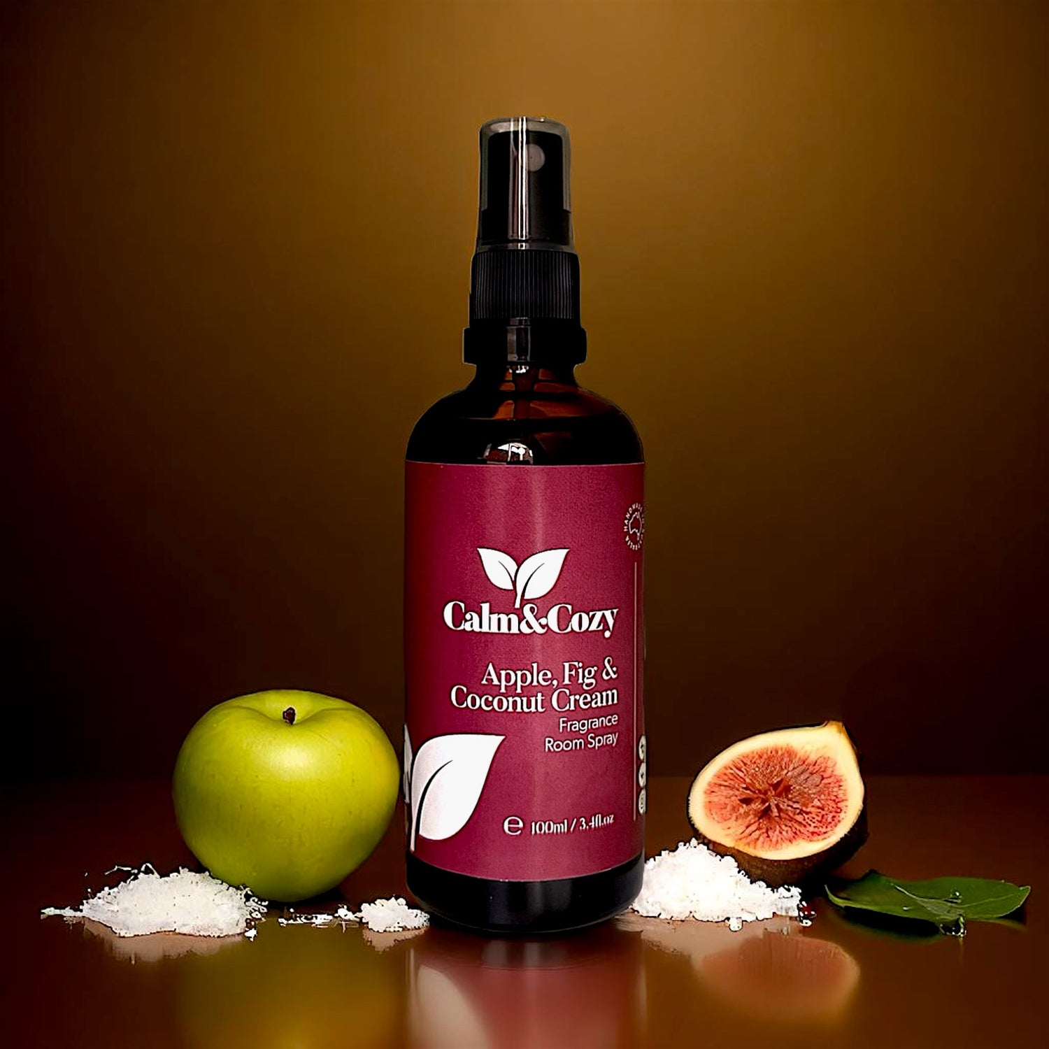 Bottle of Calm & Cozy room spray with an apple, fig, and coconut cream theme on a brown background.