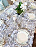 Elegant table setting with floral centerpieces and patterned tablecloth.