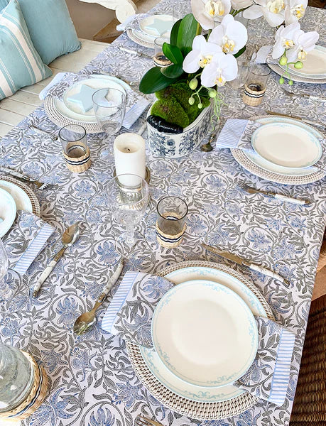 Elegant table setting with floral centerpieces and patterned tablecloth.