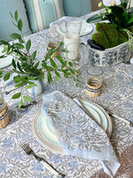 Elegant table setting with patterned tablecloth, plates, and glasses.