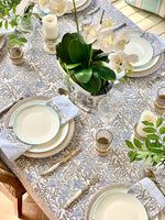 Elegant table setting with floral centerpieces and patterned tablecloth.