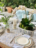 Elegant outdoor table setting with floral arrangements, candles, and patterned tablecloth.