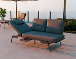Outdoor lounge chair with cushions on a patio with a scenic background