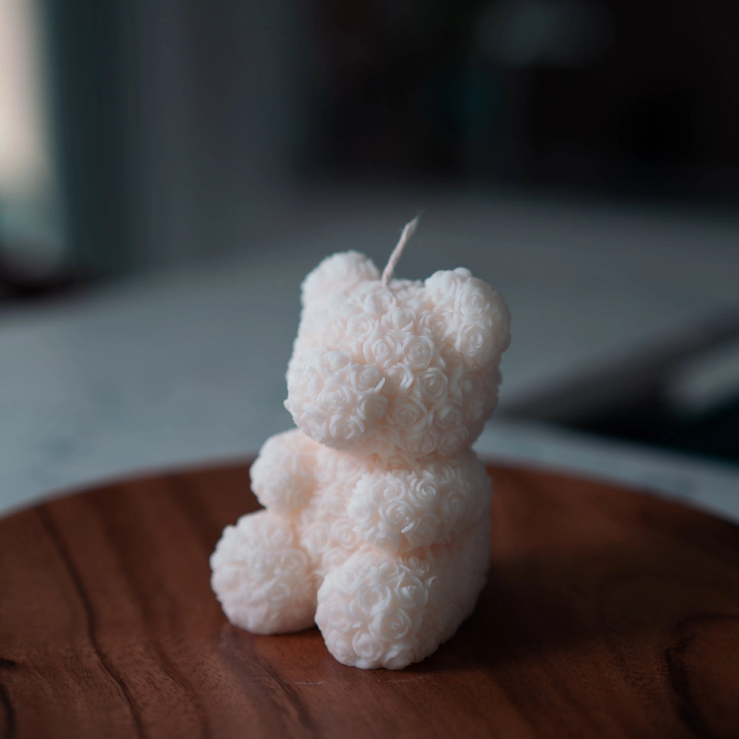 White bear-shaped candle on a wooden surface with a blurred background