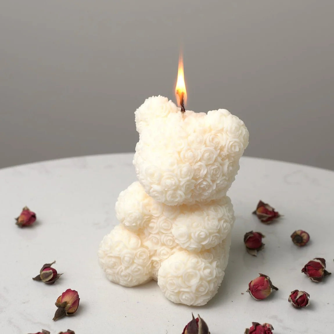 White bear-shaped candle with a flame on a gray background