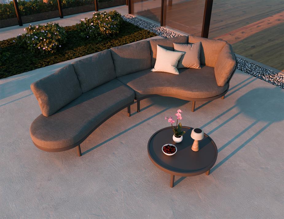 Outdoor patio set with a curved sectional sofa and round coffee table on a concrete patio.