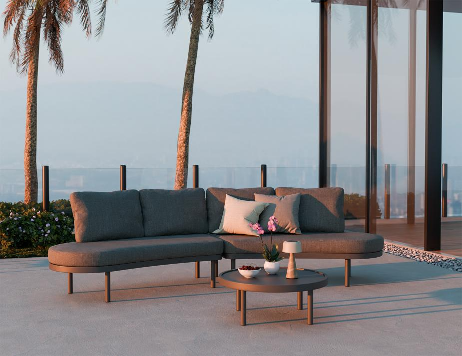 Outdoor patio set with a sofa and coffee table on a patio with palm trees in the background.
