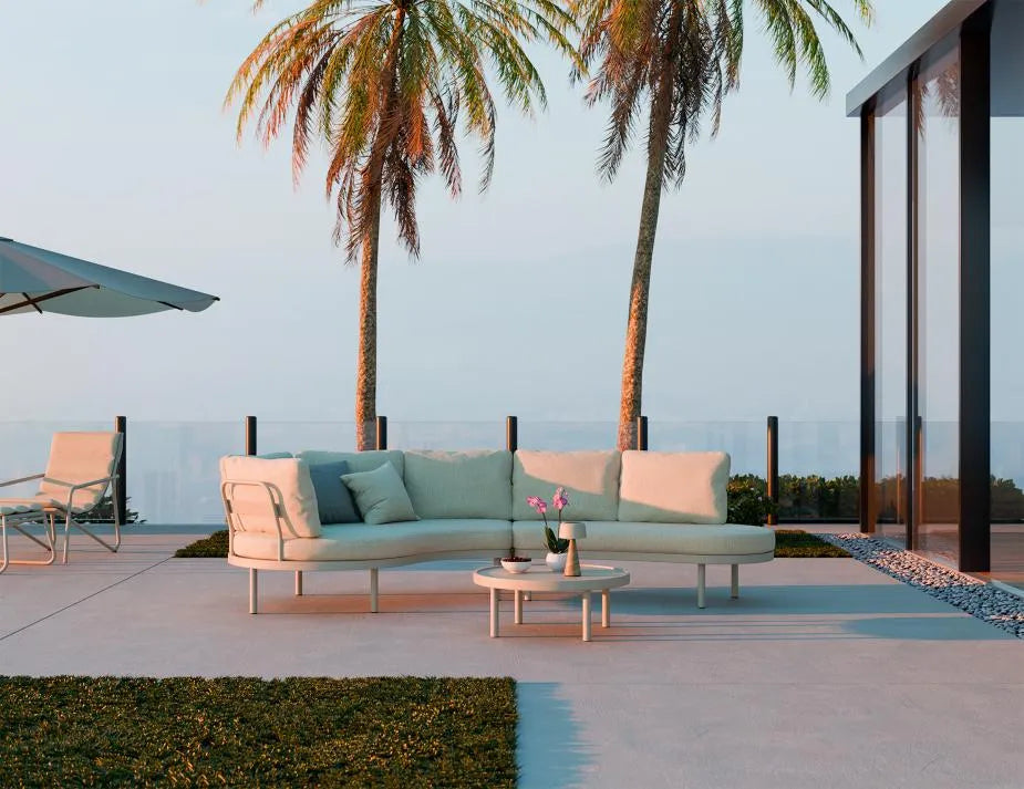 Outdoor patio with a modern sofa, coffee table, and palm trees.