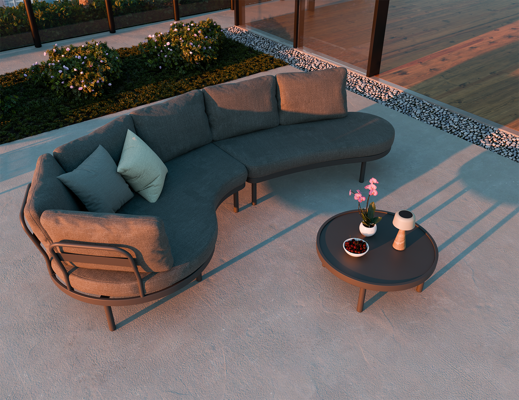 Outdoor patio set with a curved sofa, armchair, and small table on a concrete patio.