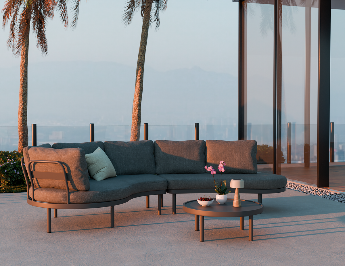 Outdoor patio set with a sectional sofa and coffee table in a tropical setting.