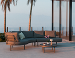 Outdoor patio set with a sectional sofa and coffee table in a tropical setting.
