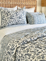 Floral-patterned bedding set on a bed with a wicker headboard.