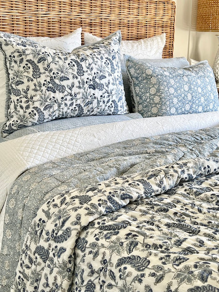 Floral-patterned bedding set on a bed with a wicker headboard.
