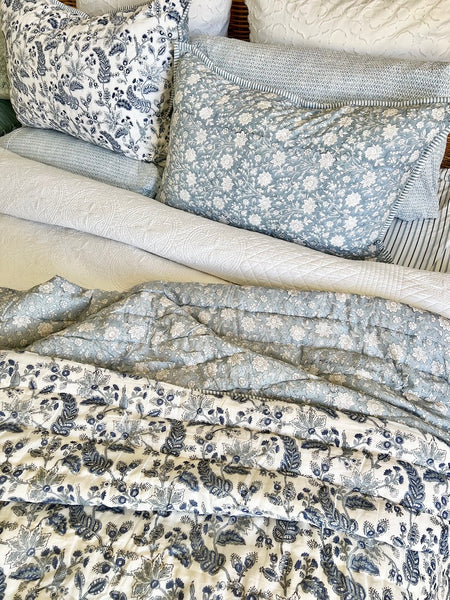 Collection of patterned pillows and fabric swatches on a neutral background