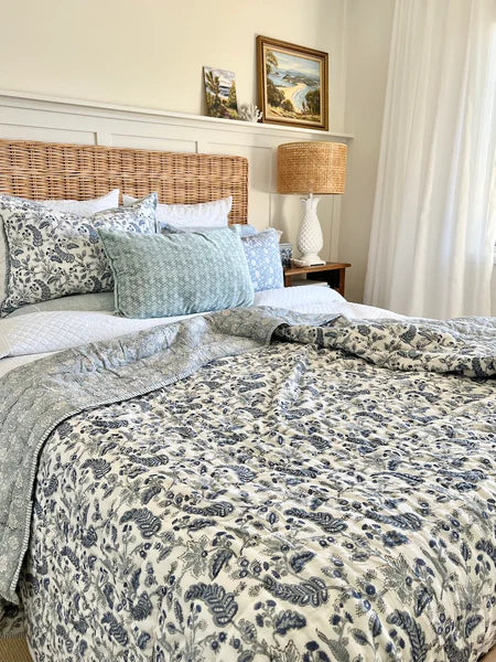 Bedroom with floral bedding, wicker headboard, and framed artwork on the wall.
