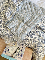 Floral-patterned fabric with a bottle, book, and glasses on a wooden surface