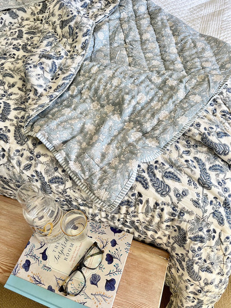 Floral-patterned fabric with a bottle, book, and glasses on a wooden surface