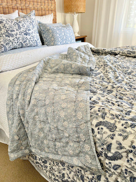 Bed with floral bedding and a lamp in a bedroom setting