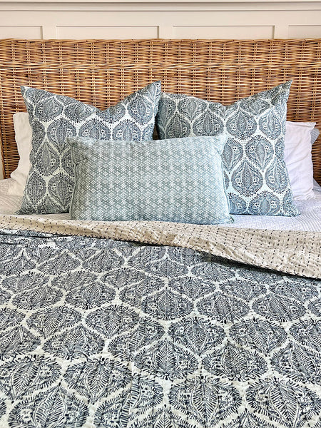 Patterned bedding with pillows on a wicker bed