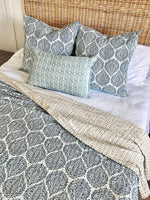 Bed with patterned bedding and pillows in a home setting