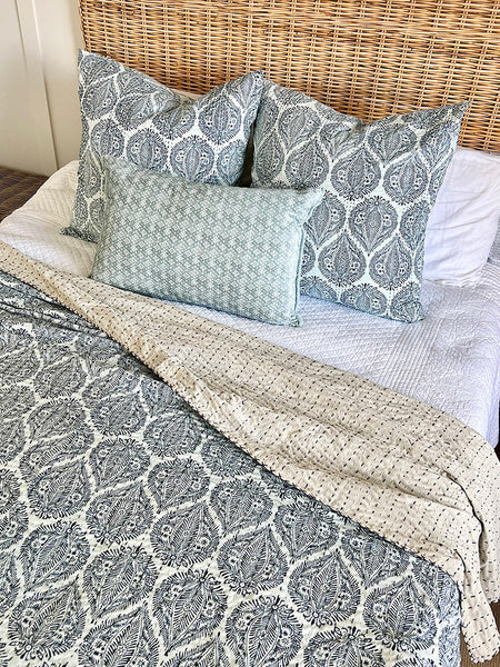 Bed with patterned bedding and pillows in a home setting