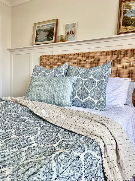Bed with patterned bedding and pillows in a bedroom setting.