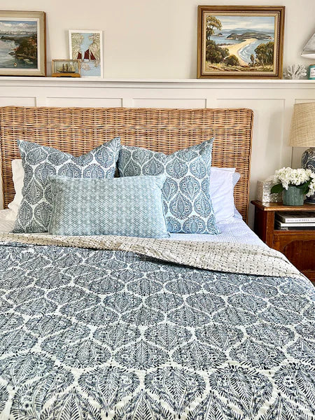 Bedroom with wicker headboard, patterned bedding, and framed artwork on the wall.
