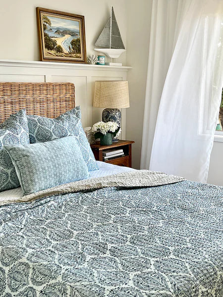 Bedroom with wicker headboard, patterned bedding, and decorative items.