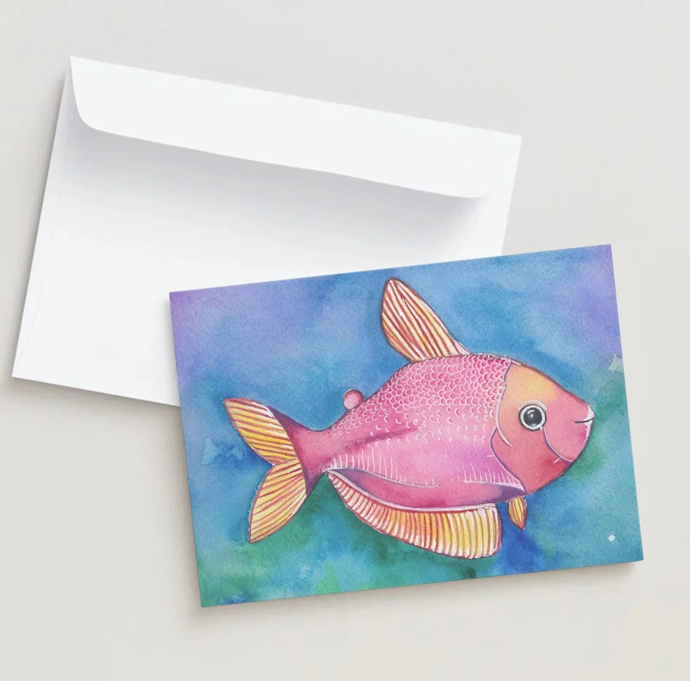 Card with a pink fish illustration on a watercolor background, accompanied by a white envelope.