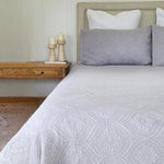Bed with gray quilt and pillows in a bedroom setting