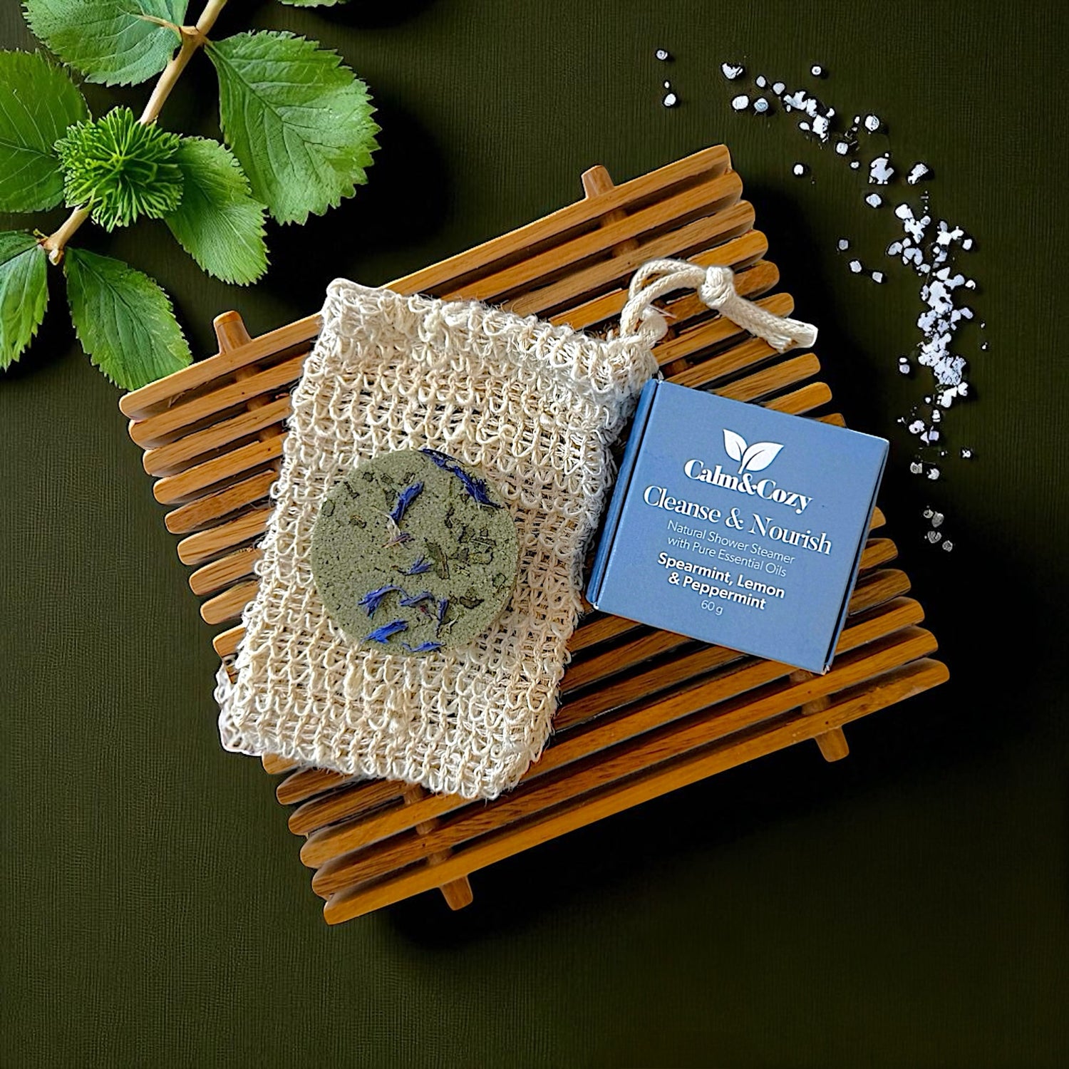 Natural soap bar with a mesh pouch and a box labeled 'Calm & Cozy' on a dark background.