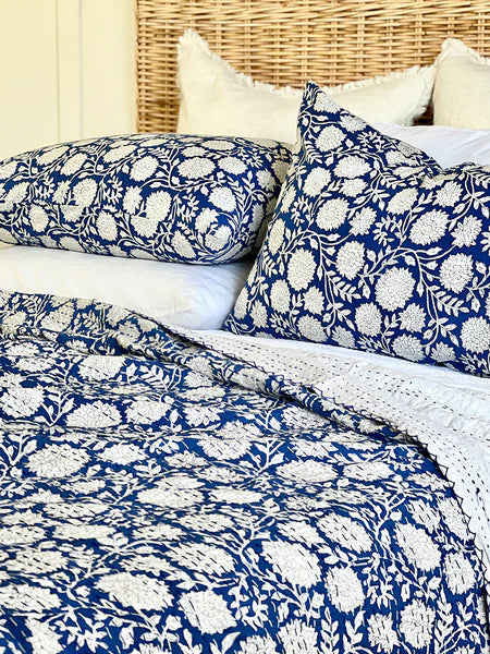Bed with blue and white floral patterned bedding and pillows.